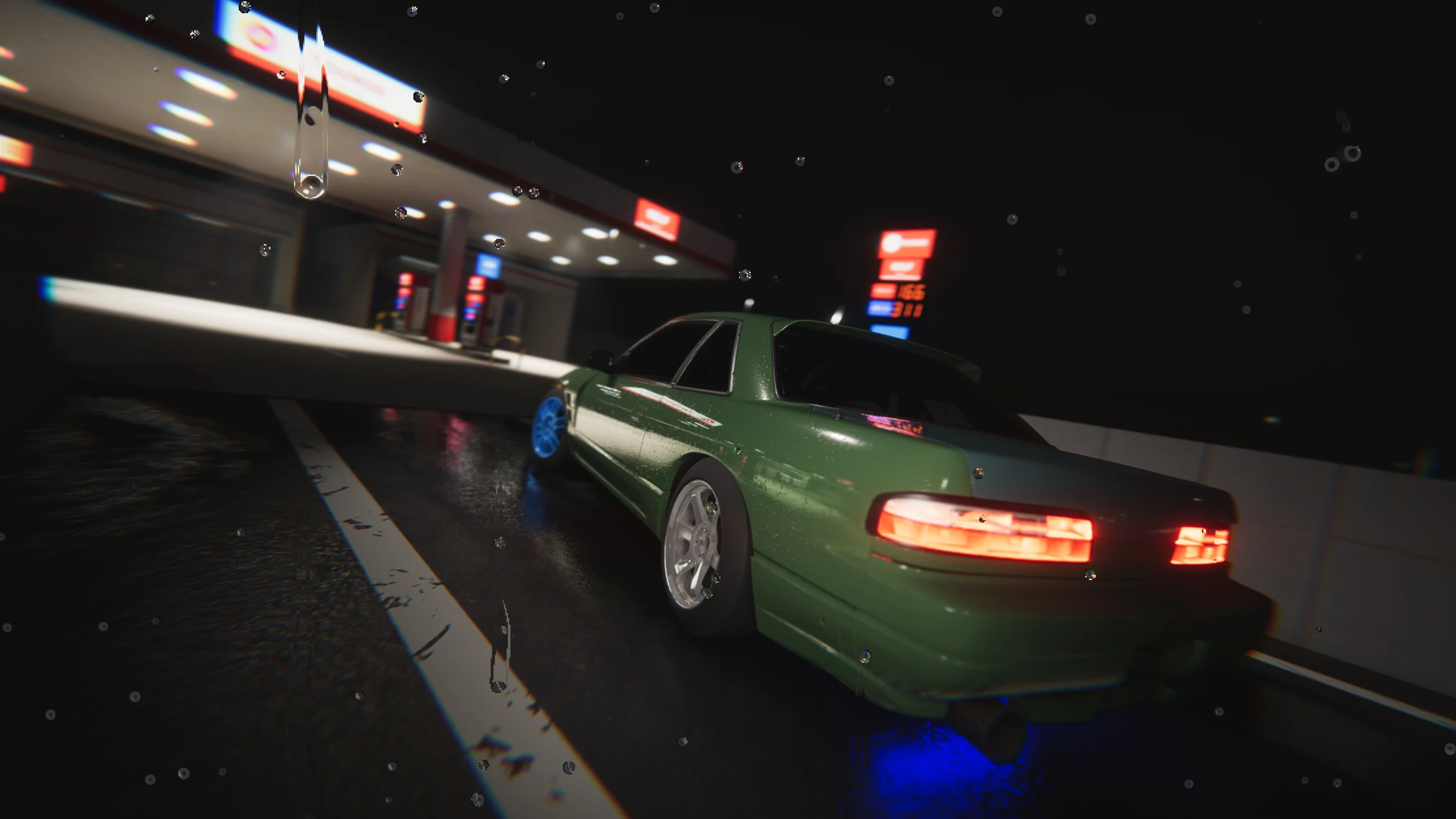 Green coupe with blue front wheels and silver rear wheels parked beneath fuel station lights on a rainy night