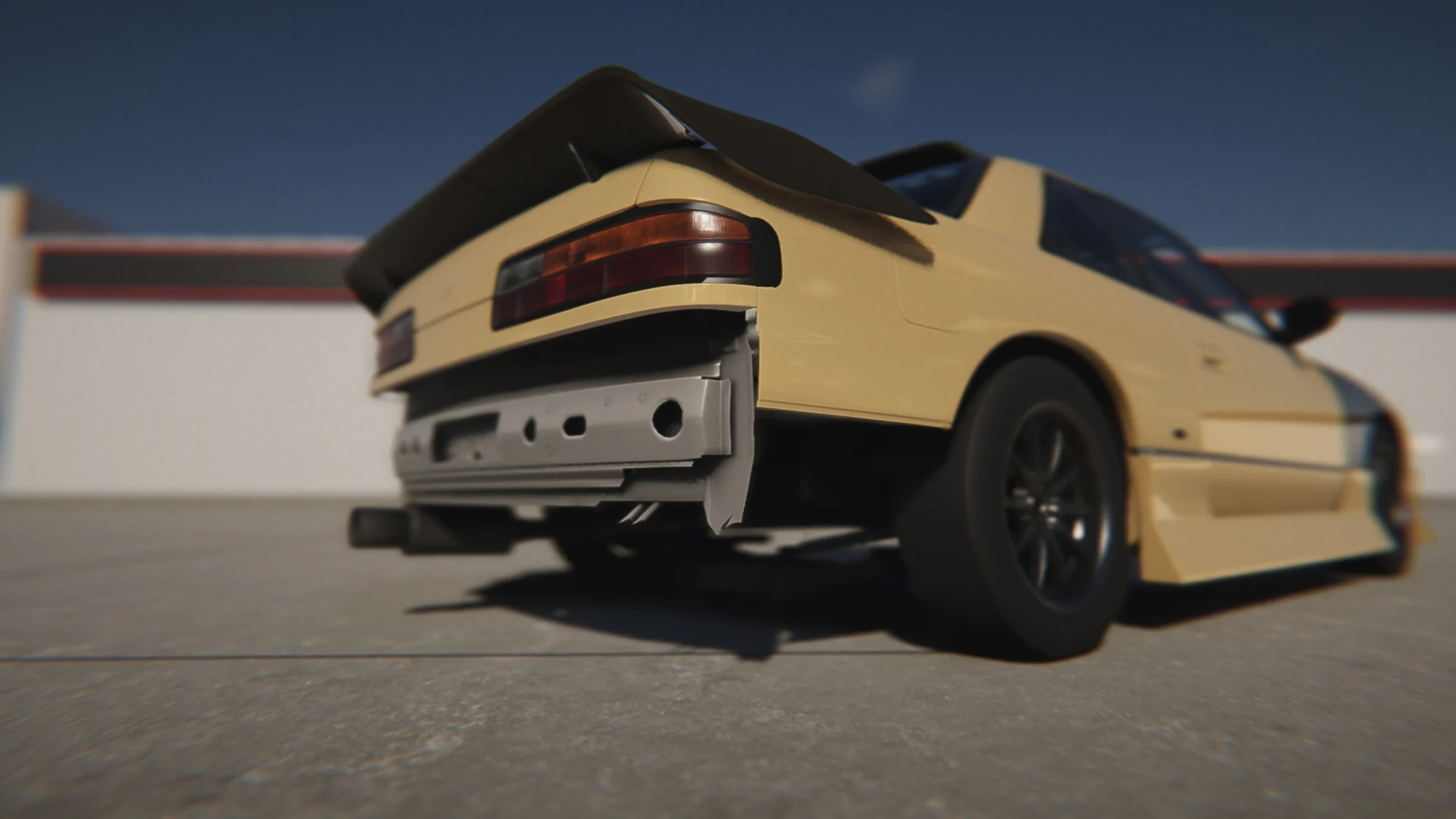 Pale-yellow coupe with dark wheels and a large rear wing, photographed from a low rear angle in daylight