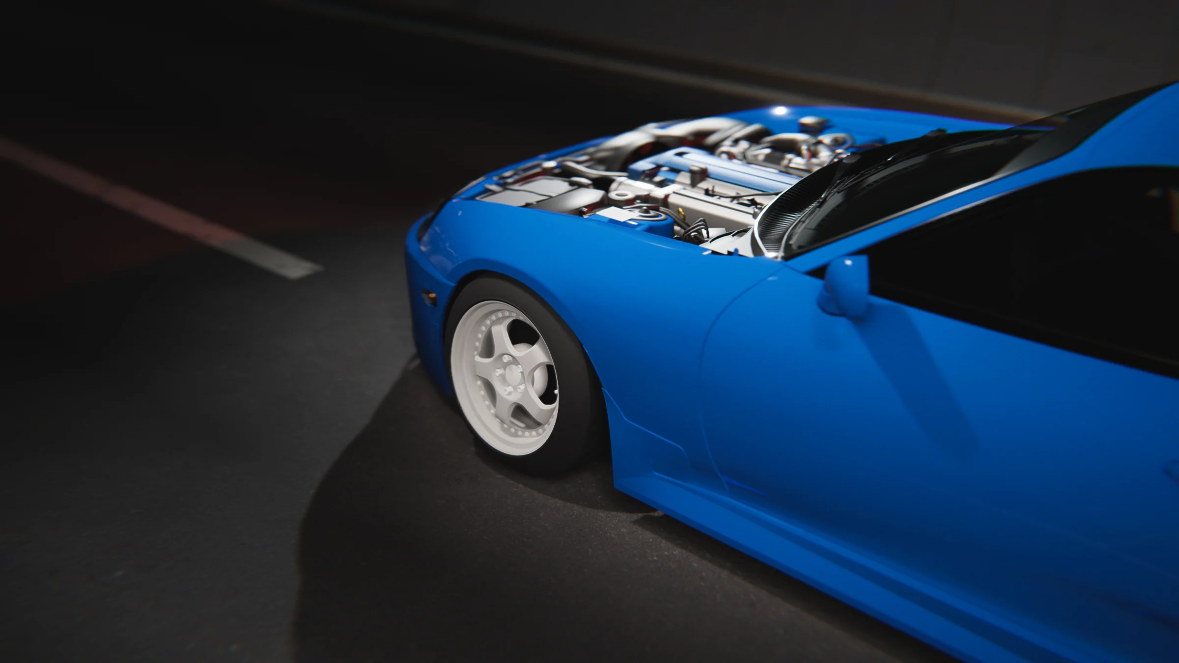 Blue coupe with white wheels and an exposed engine bay, photographed from above