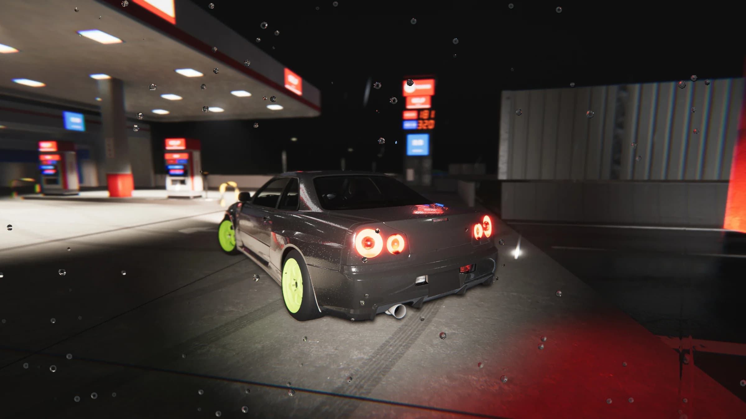 Rear view of the dark coupe with lime-green wheels beneath the fuel station lights