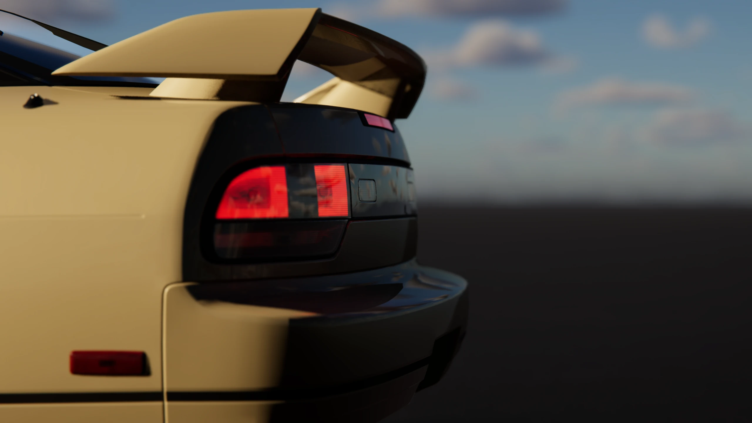 Close view of a coupe's rear spoiler and illuminated tail light