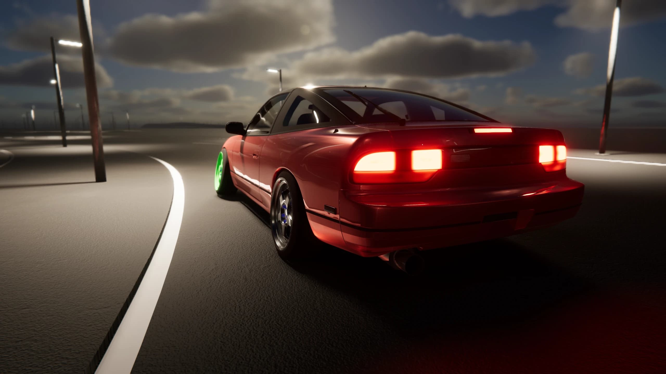 Red coupe entering a bend under a cloudy evening sky