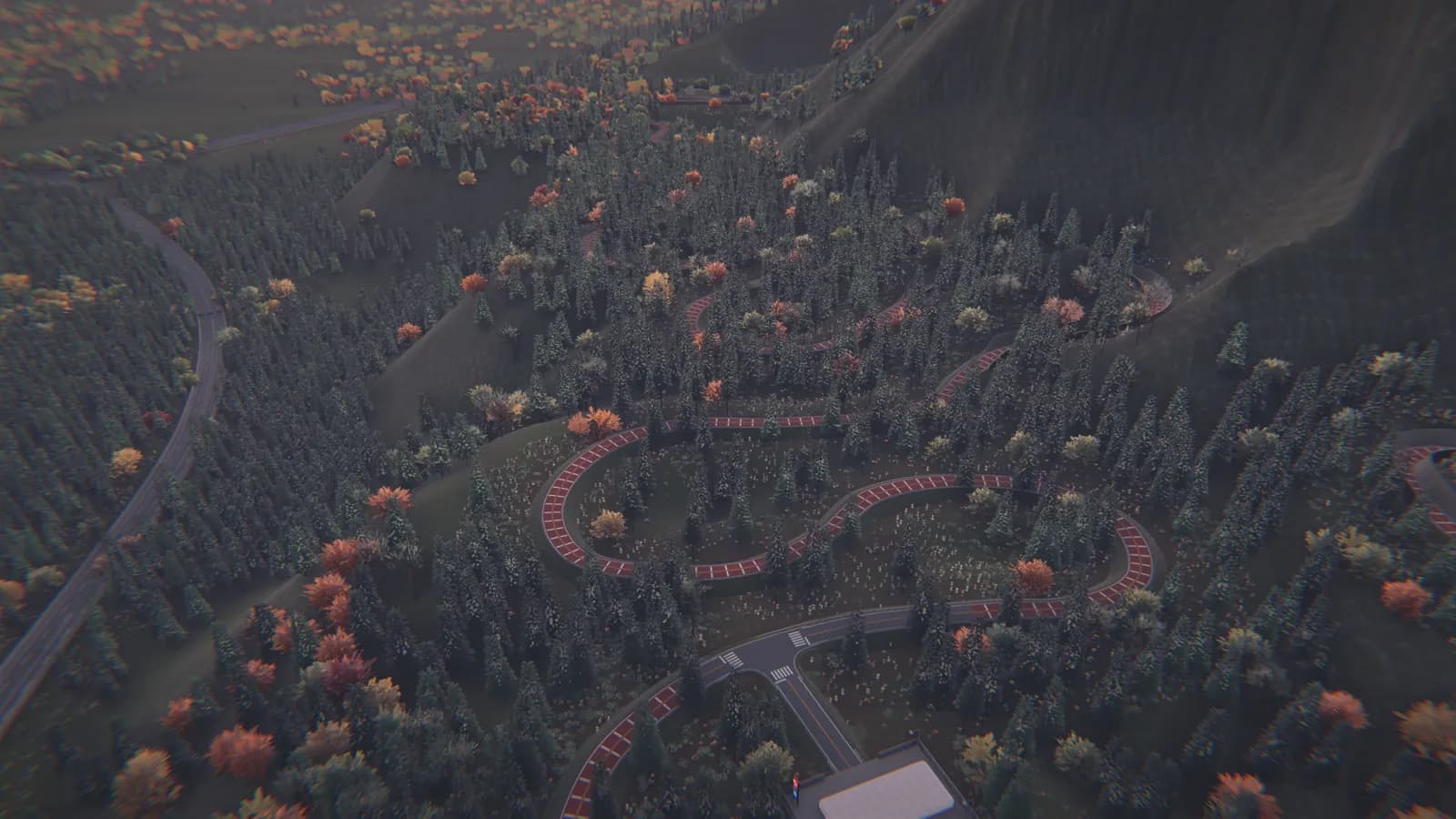 Aerial view of a road with tight switchbacks climbing a forested mountainside, with a building at the bottom