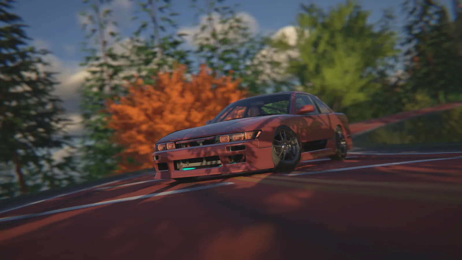 Front view of the red coupe at the edge of a corner with trees and an orange maple behind it