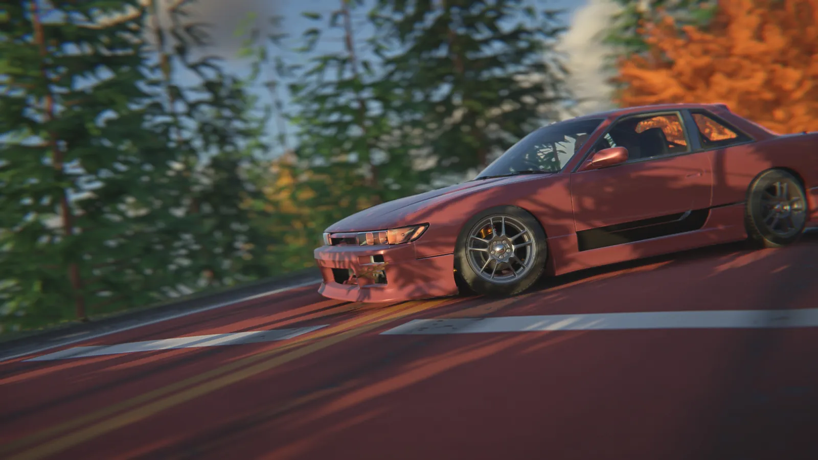 Side view of the red coupe sliding along the road with the wheel turned and dappled shadows across the bodywork