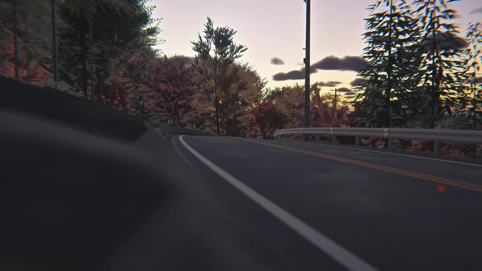 Low view beside the car looking along a road with a white edge line, a yellow centre line, a guardrail and autumn trees at dusk