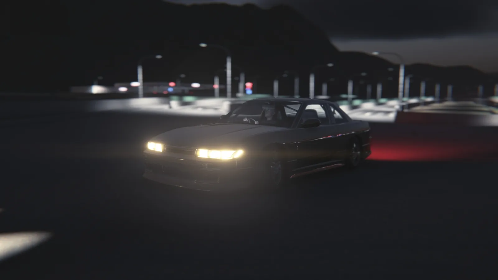 Coupe with headlights on on a dark road lined with street lamps, with mountains silhouetted behind